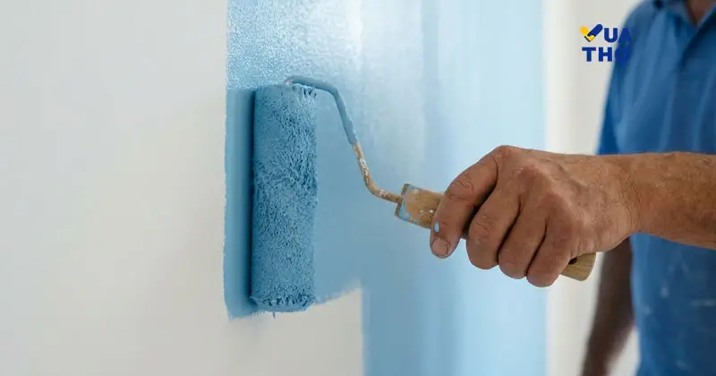 Thợ đang lăn lớp sơn nước hoàn thiện láng mịn lên bức tường đã bả bột.